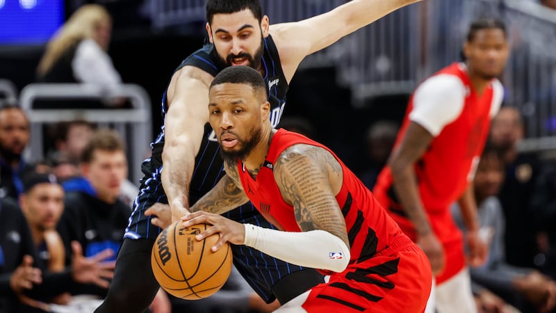 Orlando Magic center Goga Biitadze, left, reaches in as Portland Trail Blazers guard Damian...