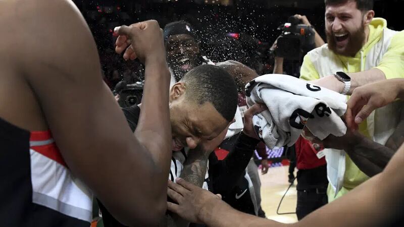 Portland Trail Blazers guard Damian Lillard, center, is doused by teammates after setting...