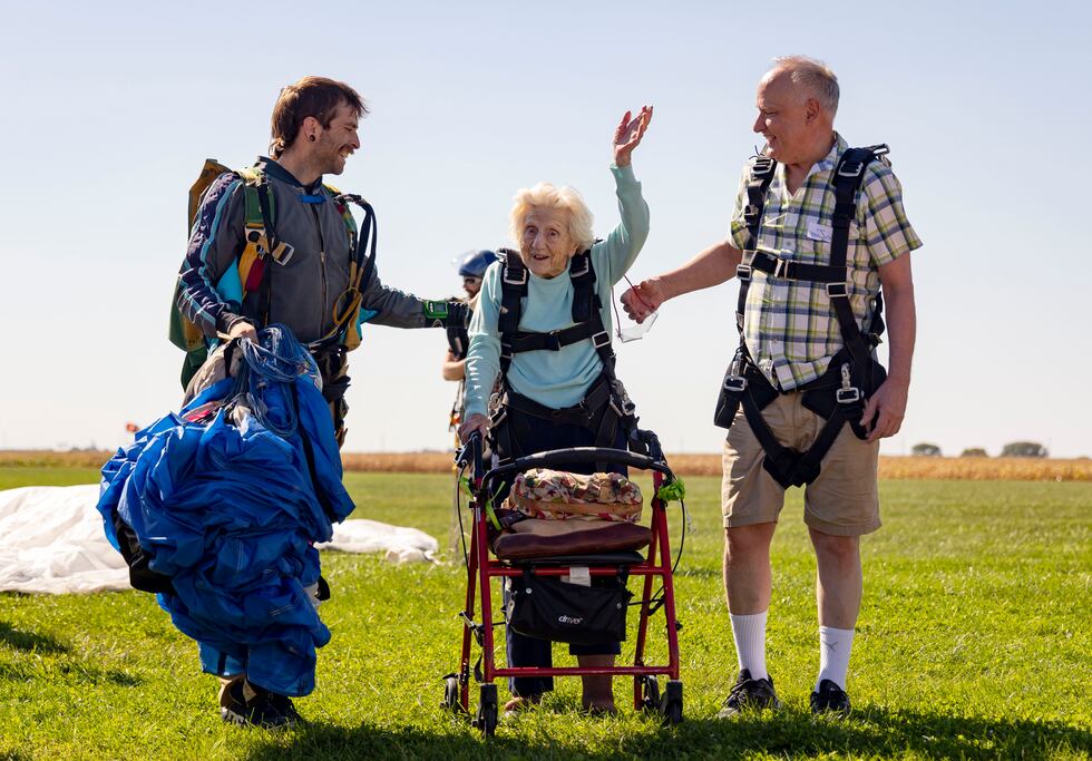 Dorothy Hoffner, 104, waves to the crowd with tandem jumper Derek Baxter, left, and friend Joe...