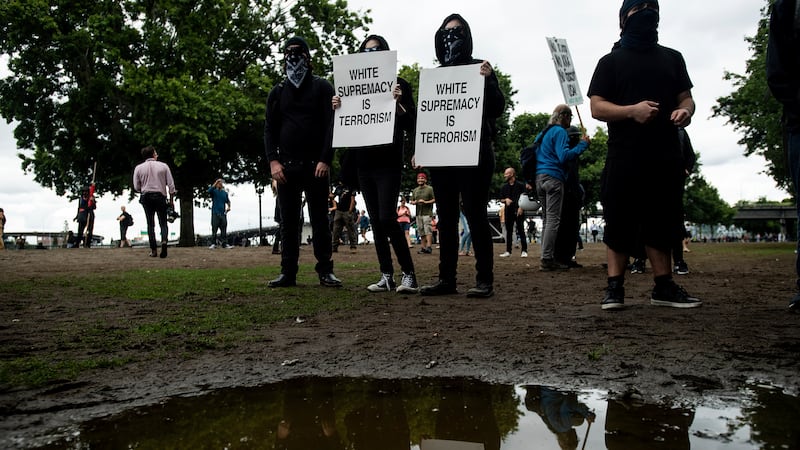 Black-clad protesters, gathered to oppose conservative groups staging an "End Domestic...