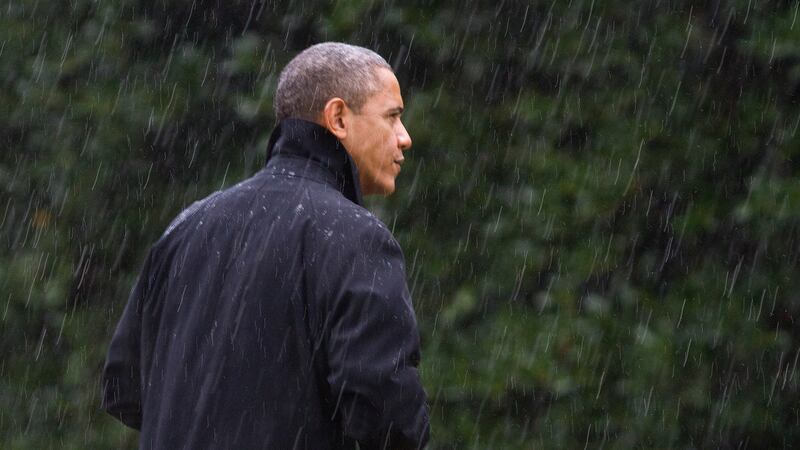 President Barack Obama walks into the White House in a driving rain after returning to...