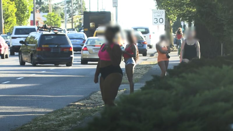 Subjects involved in a sex trafficking investigation are seen standing next to a street in...